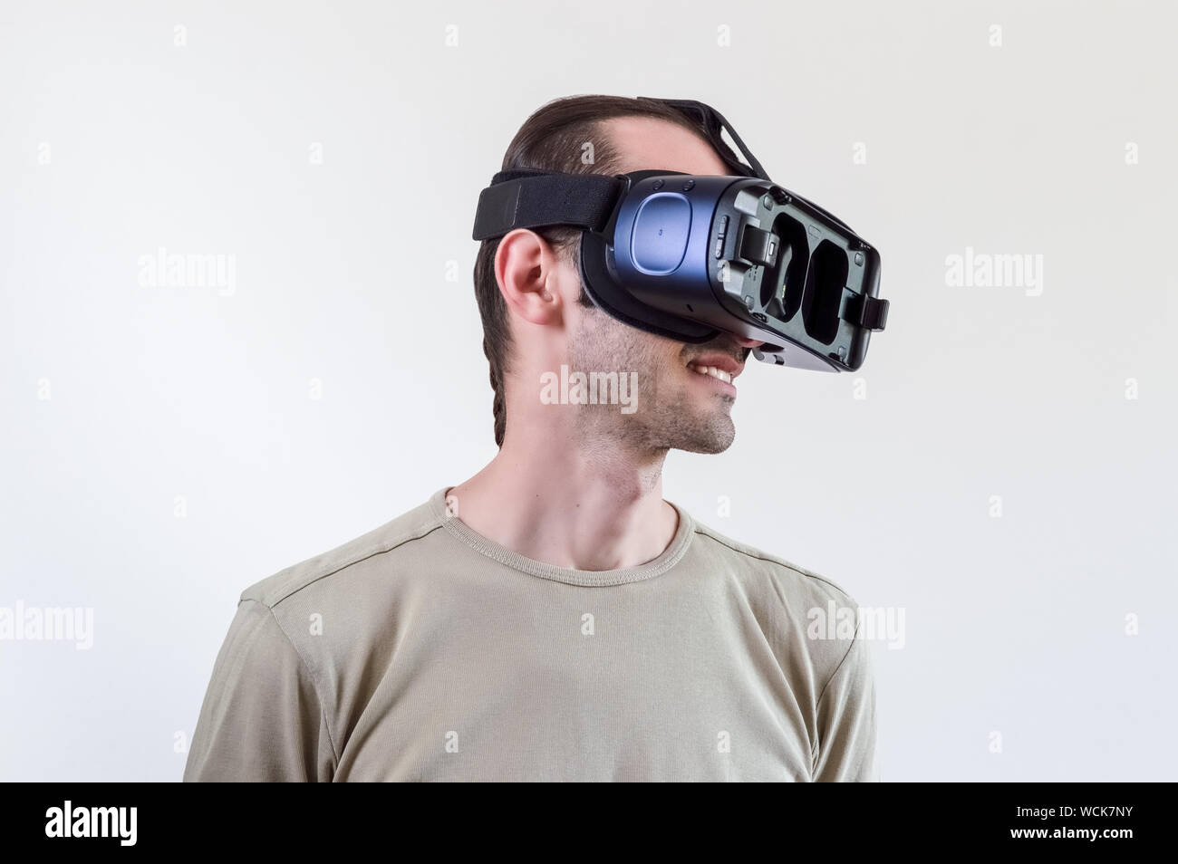 Caucasian man in t-shirt wearing virtual reality goggles on white background. Future technology concept. Stock Photo