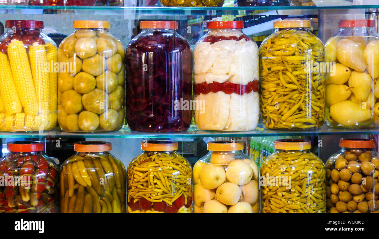 Jars of pickled vegetables: cucumbers, green pepper, plum, cabbage. Marinated and canned food. Stock Photo