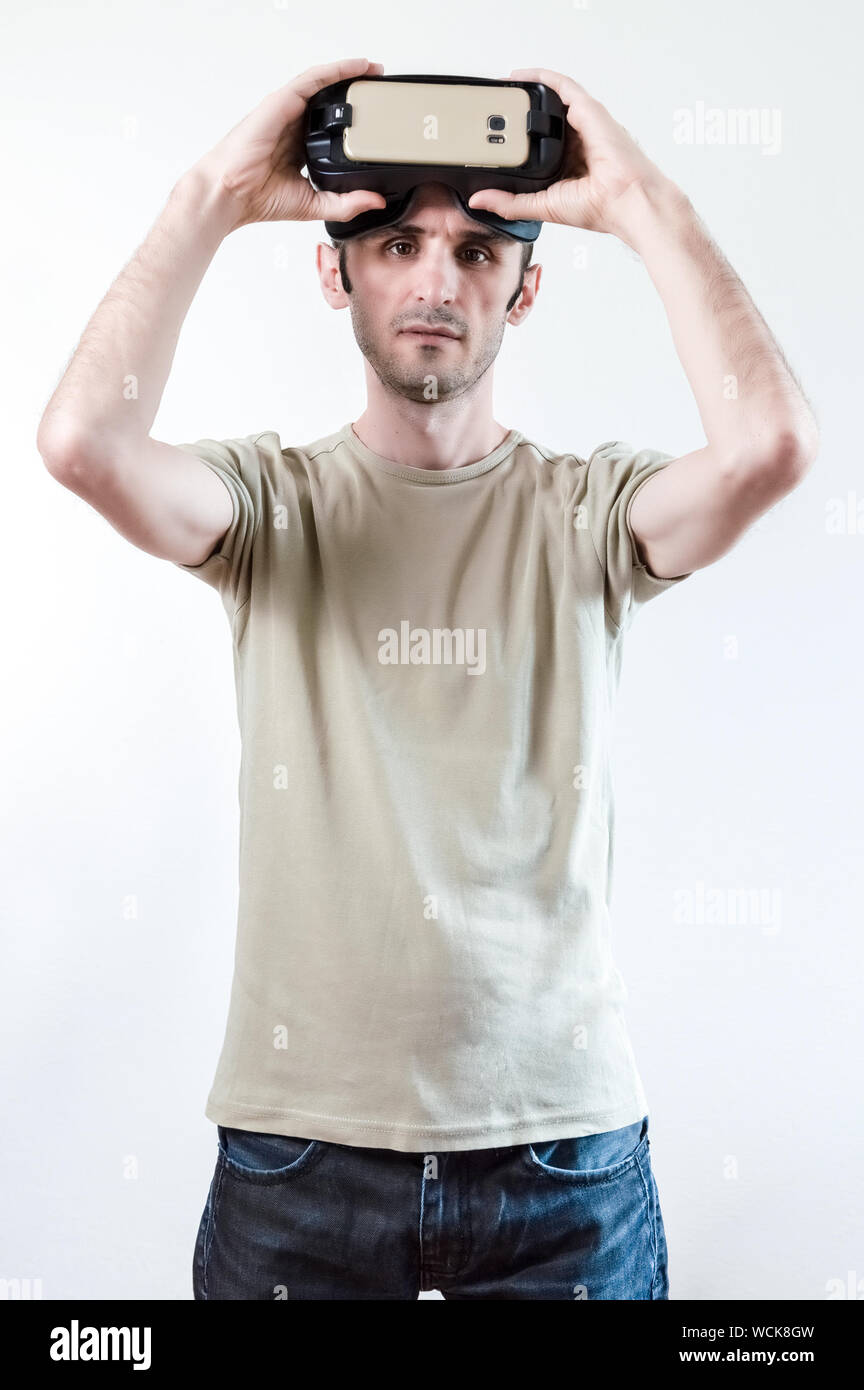 Caucasian man in t-shirt wearing virtual reality goggles on white background. Future technology concept. Stock Photo