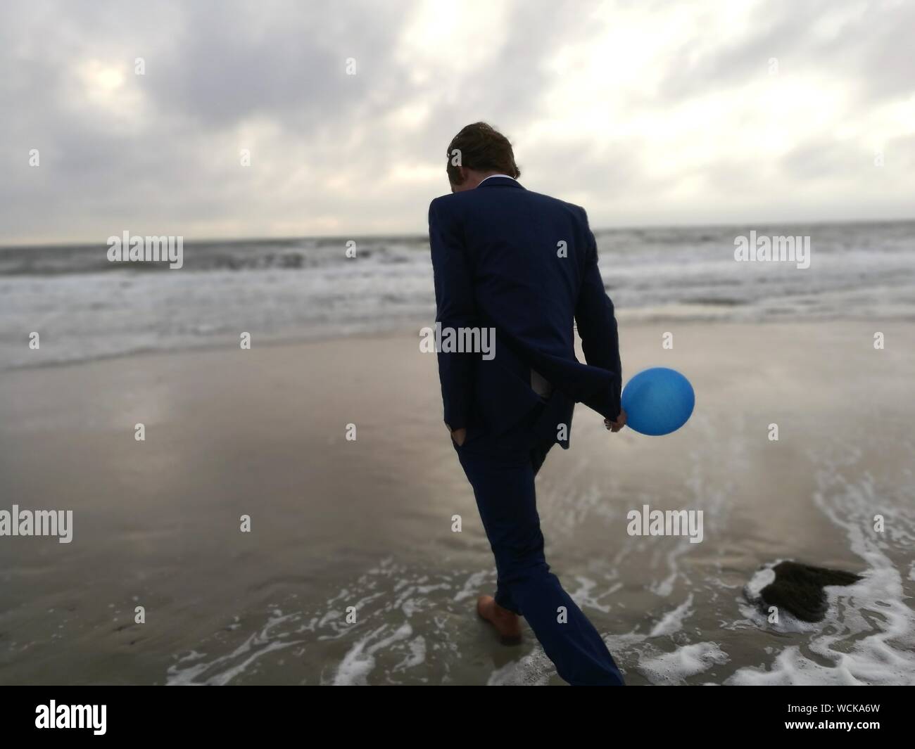 Rear View Of A Man Walking On Beach Stock Photo