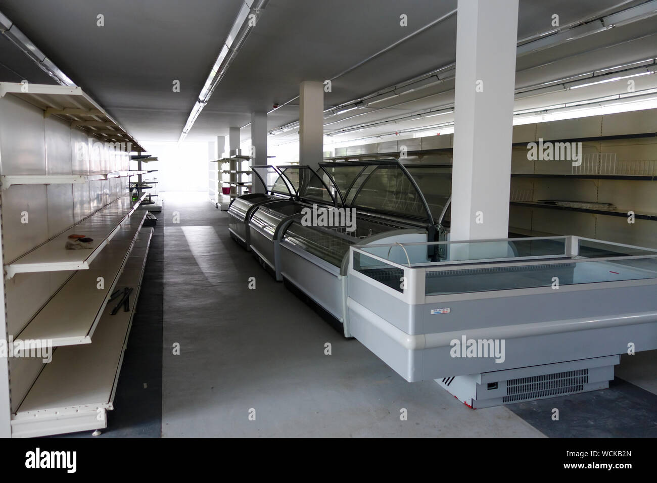 Empty shelves and chest freezers of a closed supermarket that is for