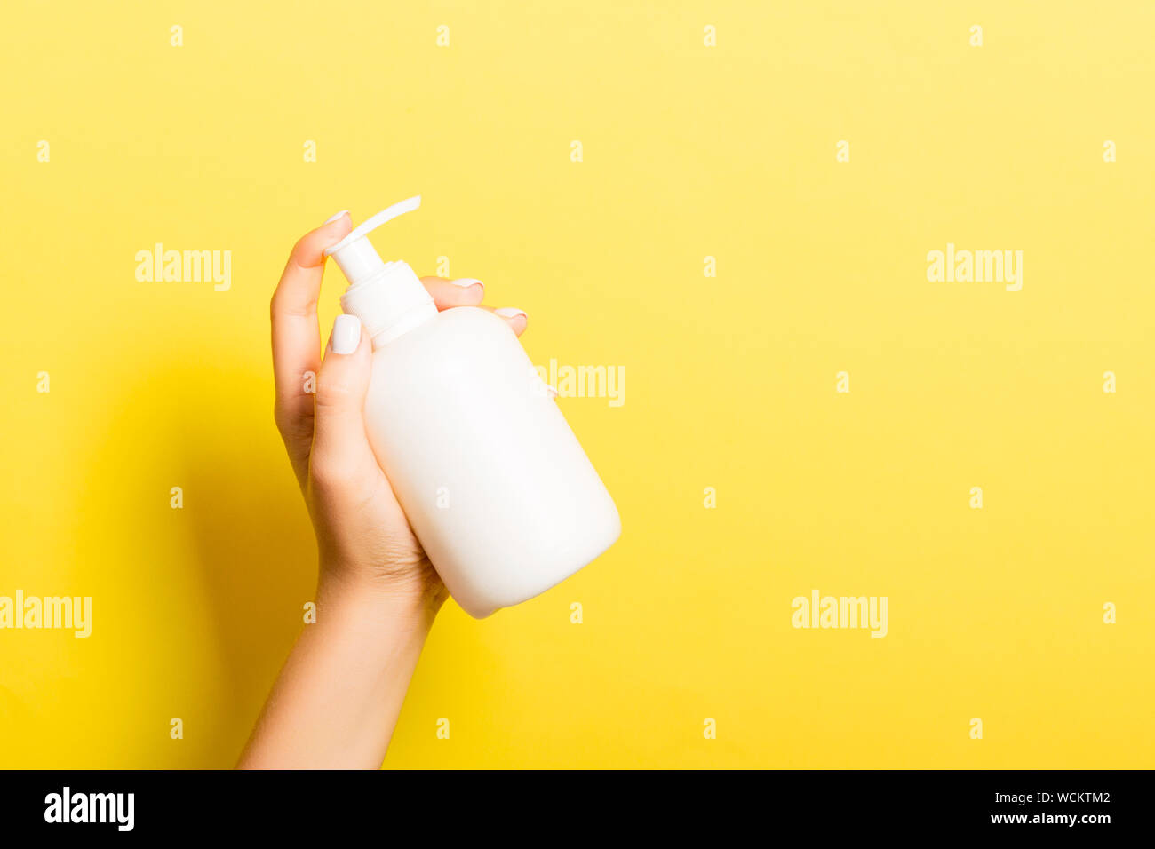 Female hand holding spray cream bottle of lotion isolated. Girl give