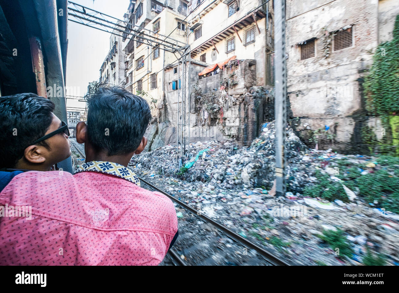 Passengers on a train passing through the slums of Delhi,India Stock Photo