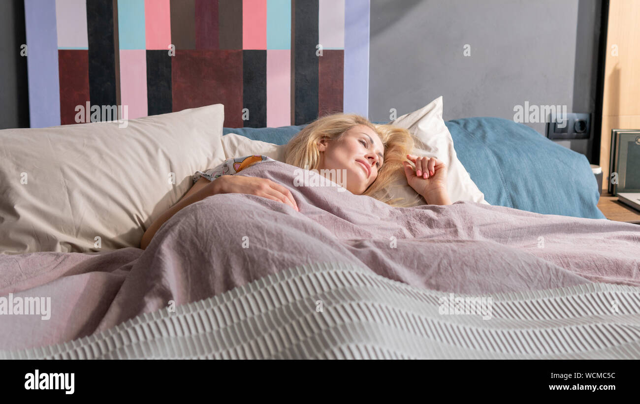 Young beautiful European woman sleeping in her bed and relaxing in the morning. Pretty millennial woman dreaming in the bed at home Stock Photo