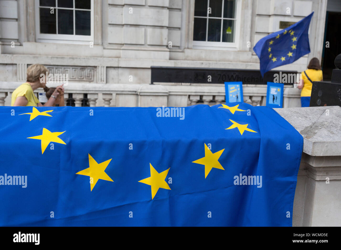 On the day that British Prime Minister Boris Johnson sought to have Parliament suspended by Queen Elizabeth, days after MPs return to work in September - and only a few weeks before the Brexit deadline, tourists walk past pro-EU Remain voters protest outside the Cabinet Office where daily Brexit contingency planning meetings take place, on 28th August 2019, in Whitehall, Westminster, London, England. Stock Photo