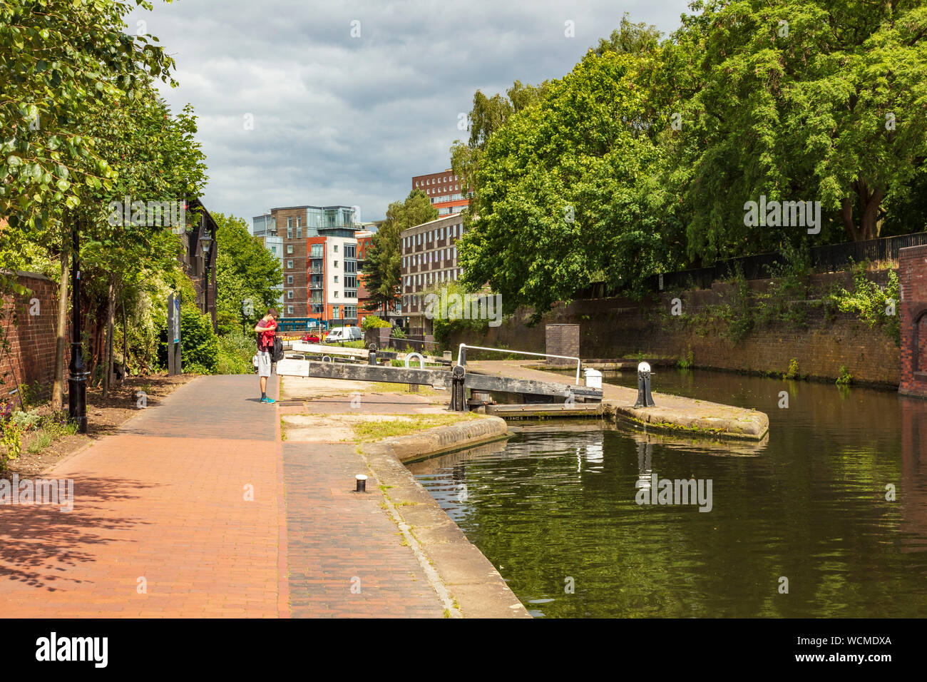 A man stands and searches his bag on the Towpath of the Birmingham and