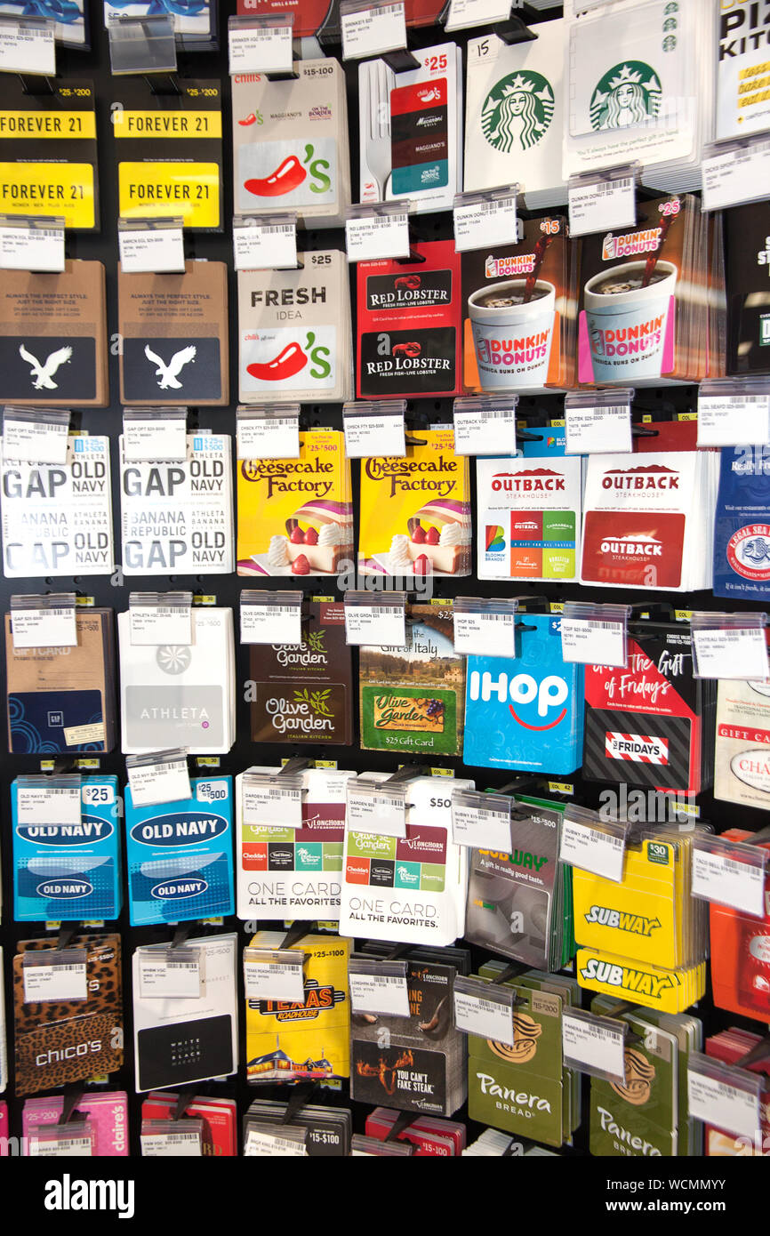 Various gift cards (restaurants, clothing stores, online stores) for sale on a store display rack. Stock Photo