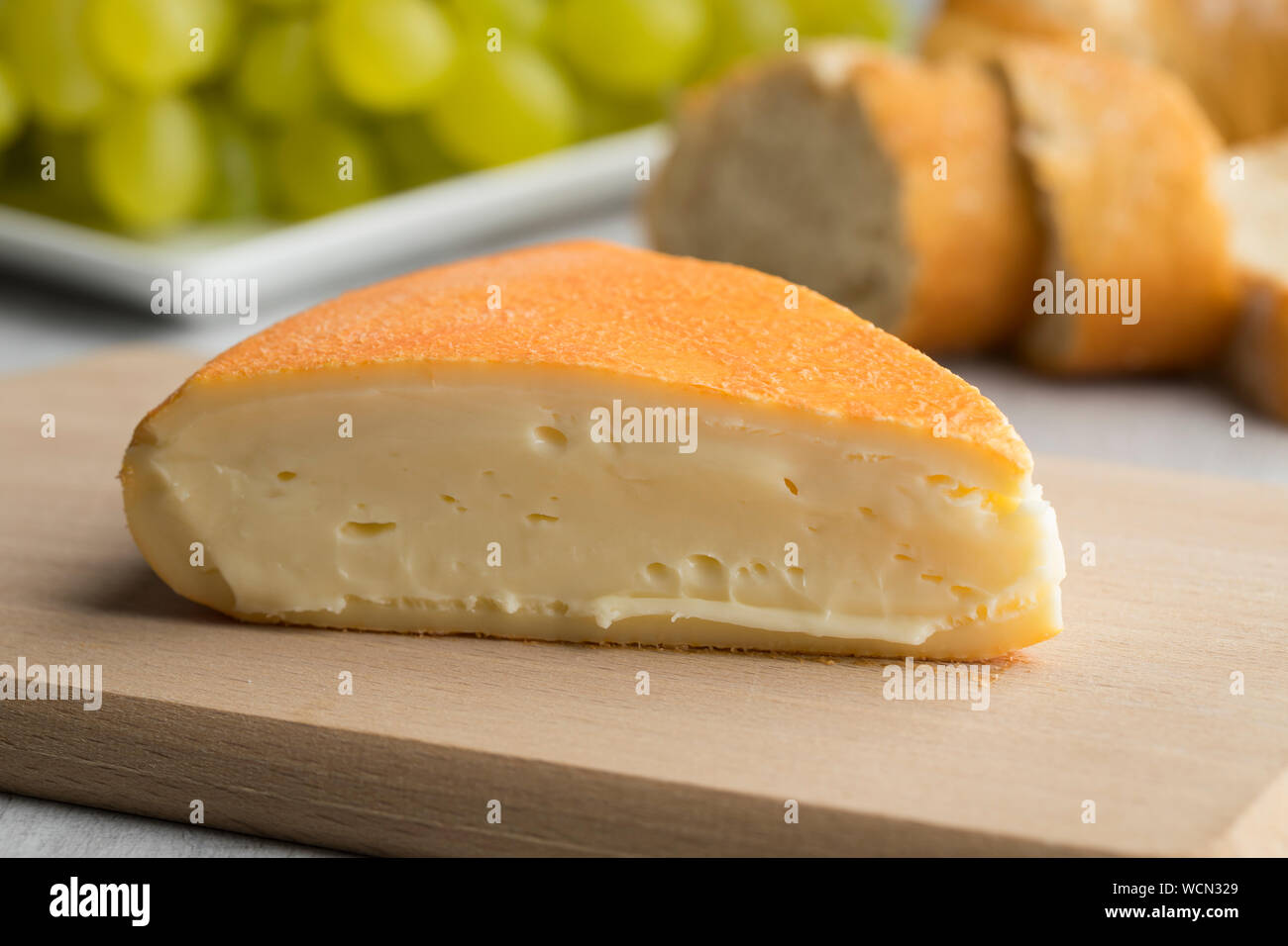 Piece of creamy French Chaumes cheese on a cutting board close up Stock Photo