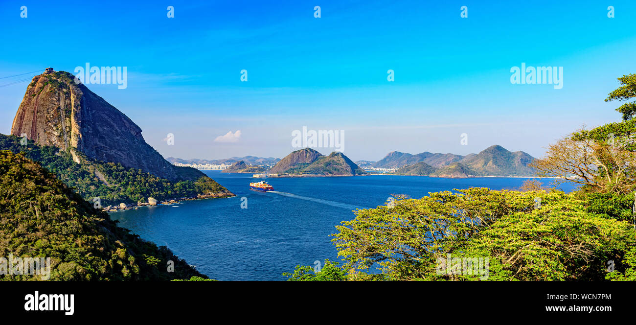 Cargo ship arriving at the entrance of the Guanabara Bay in Rio de Janeiro with forest, Sugar Loaf mountain and Niteroi city in background Stock Photo