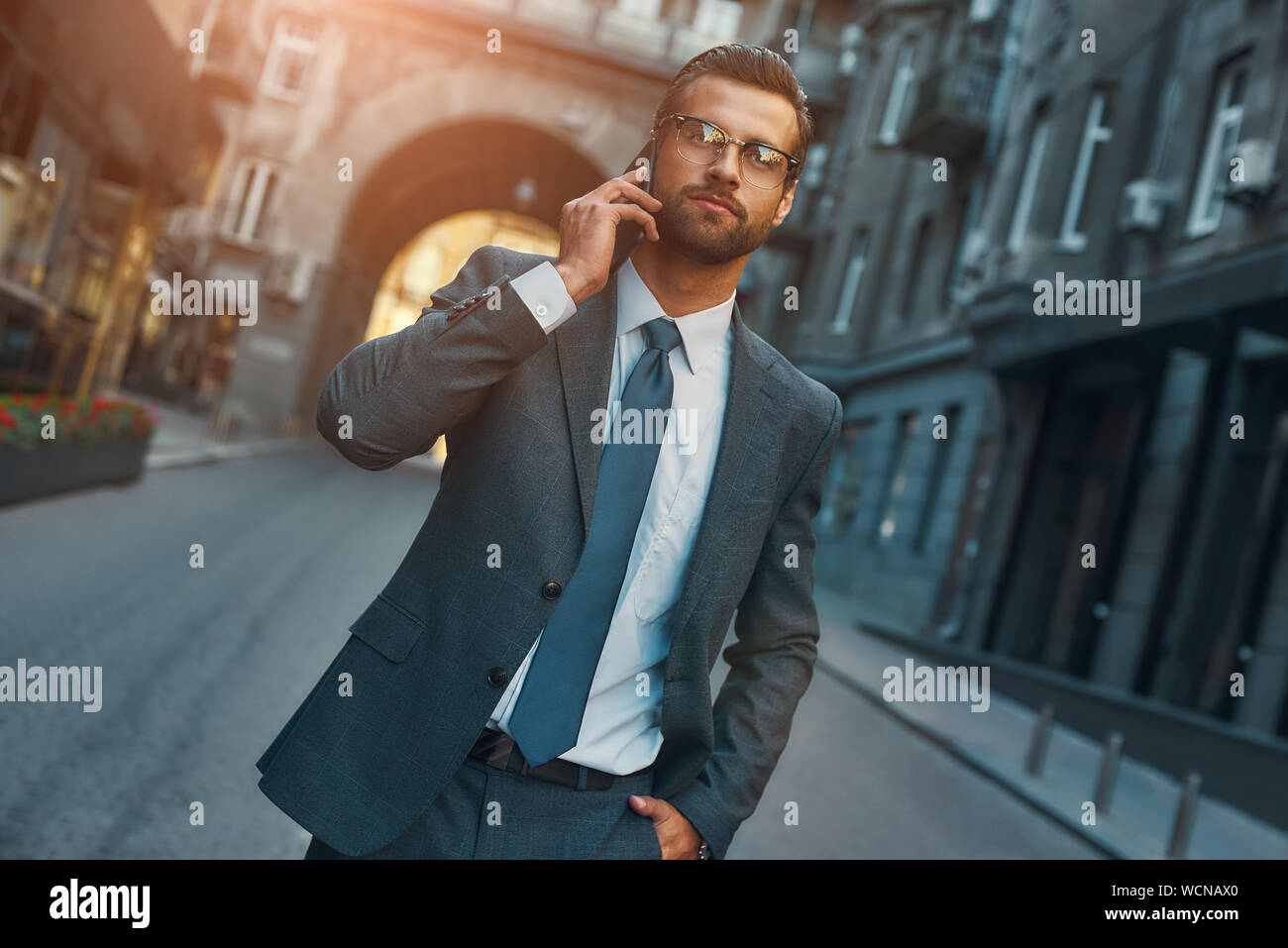 Busy man. Portrait of bearded businessman in full suit talking by phone with client while walking outdoors. Business concept Stock Photo