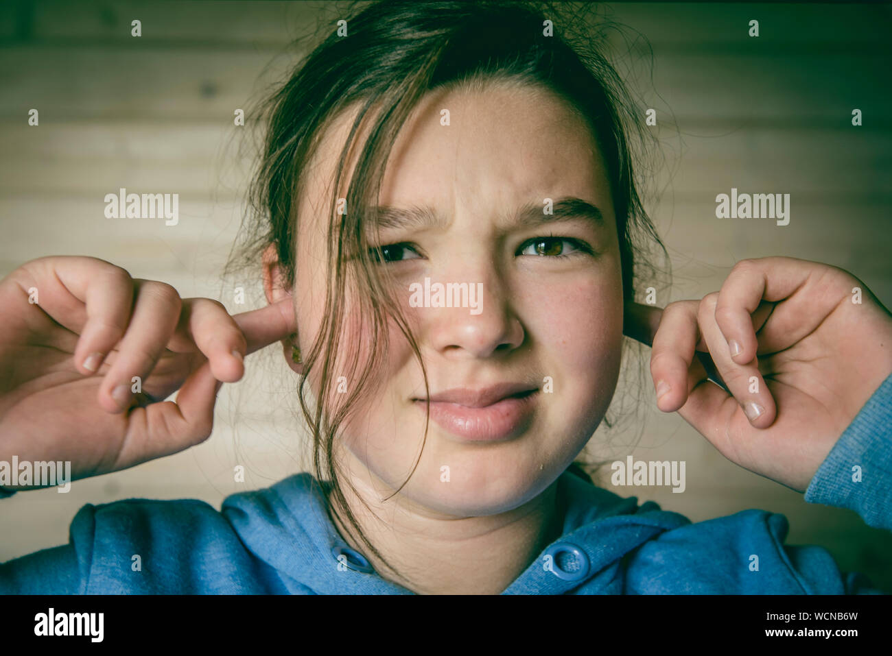Close-up Portrait Of Young Woman With Hands Covering Ears Stock Photo