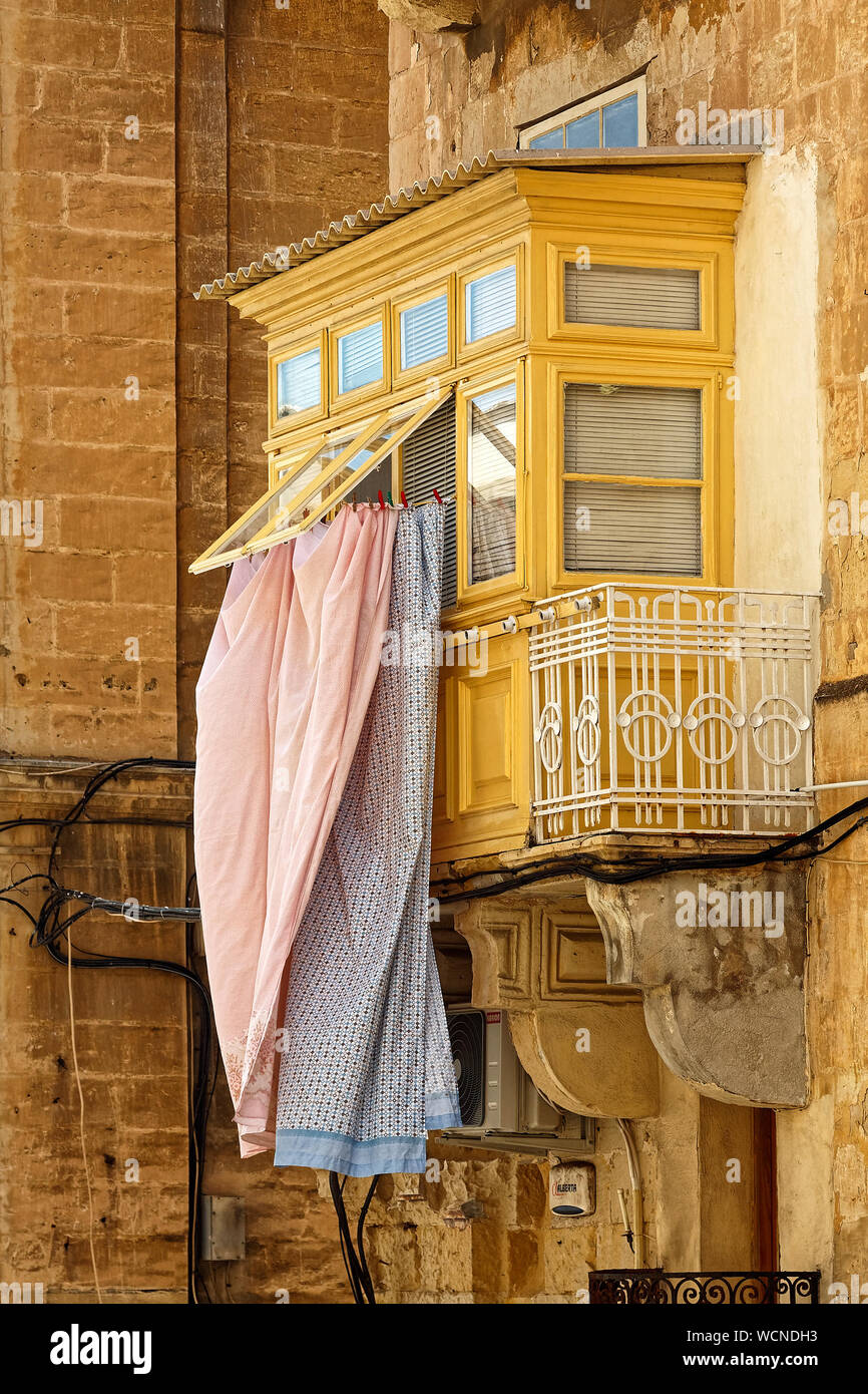 clean laundry hanging, outside window; Gallariji; Maltese balcony; many wires, wall repair, limestone building, Europe; Valletta; Malta; spring; verti Stock Photo