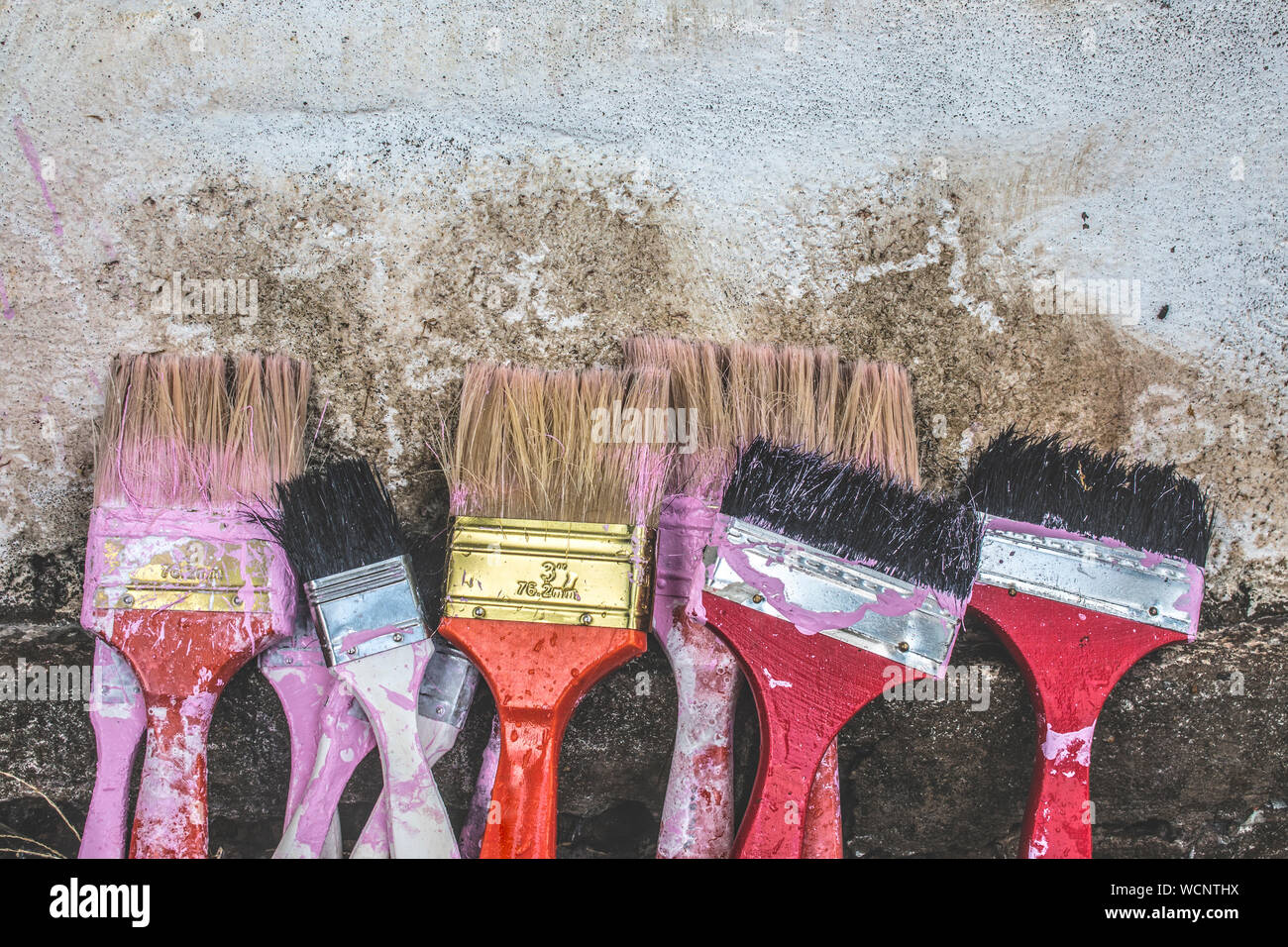 Messy Paintbrushes On Weathered Wall Stock Photo