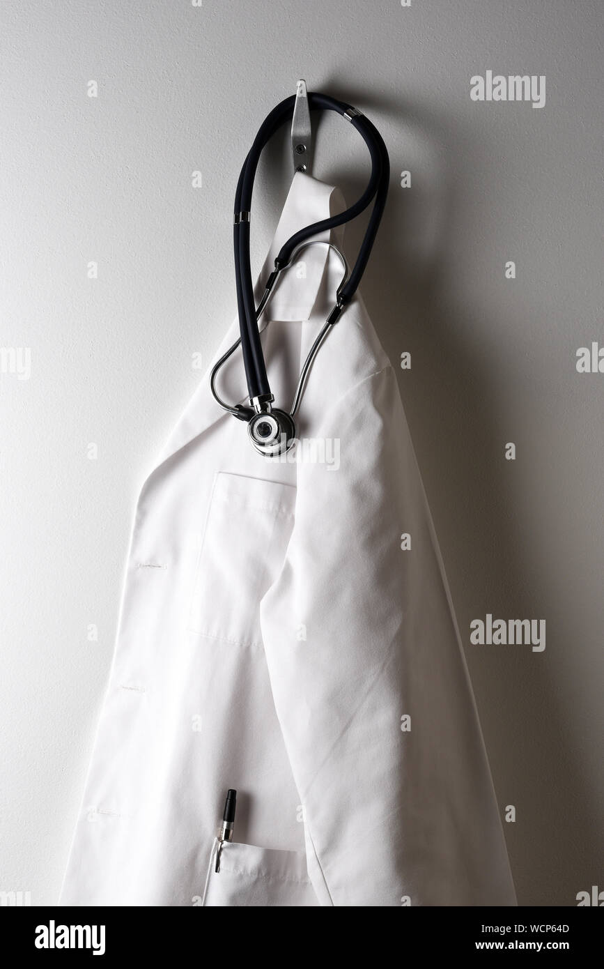 A Doctors White Lab Coat Hanging on a Hook with Stethoscope. Stock Photo