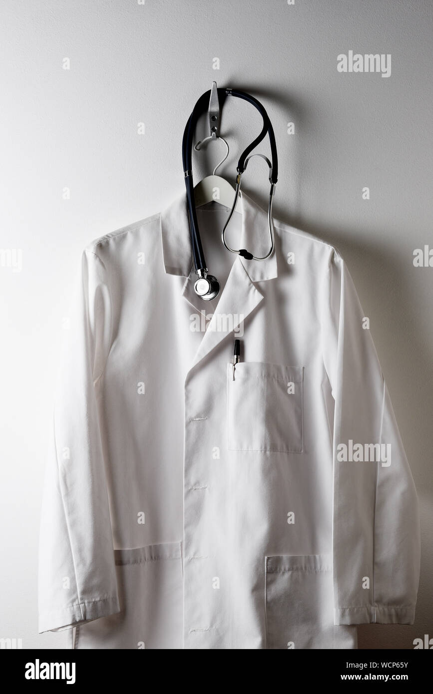 A Doctors White Lab Coat on a hanger and hook with Stethoscope. Stock Photo