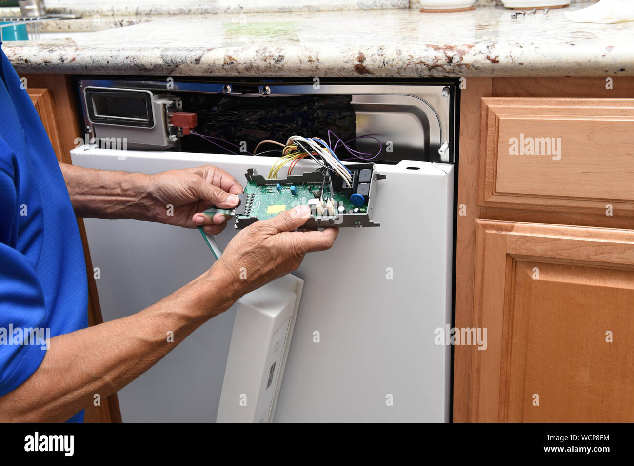 Closeup of a appliance repairman unplugging the control panel to a broken dishwasher. Stock Photo