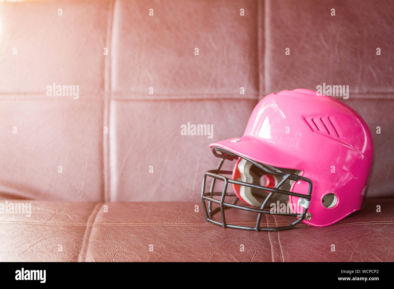 Close-up Of Pink Sports Helmet On Brown Sofa Stock Photo