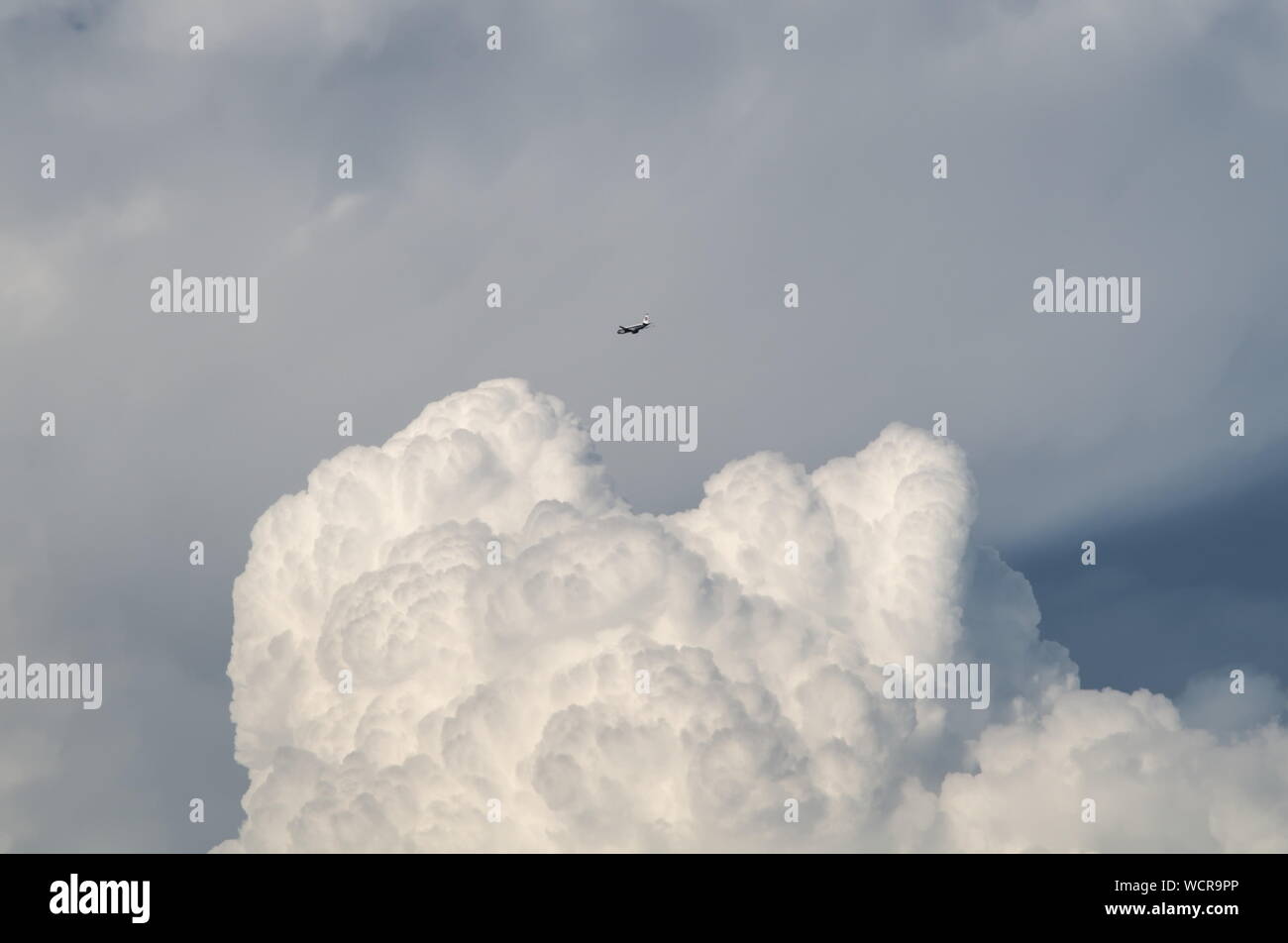 Plane Flying Above Huge Cloud Stock Photo