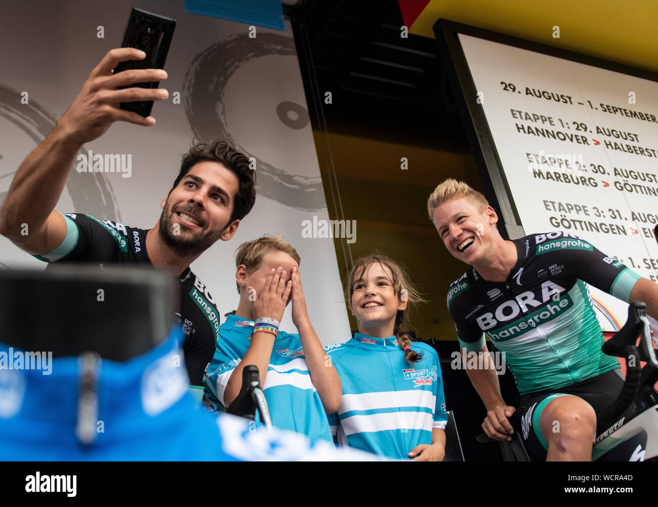 Hanover, Germany. 28th Aug, 2019. Cycling: Germany Tour, team presentation: Michael Schwarzmann (l) and Pascal Ackermann from Germany of Team Bora-hansgrohe (2nd from left) take pictures with two sponsored children. Credit: Bernd Thissen/dpa/Alamy Live News Stock Photo