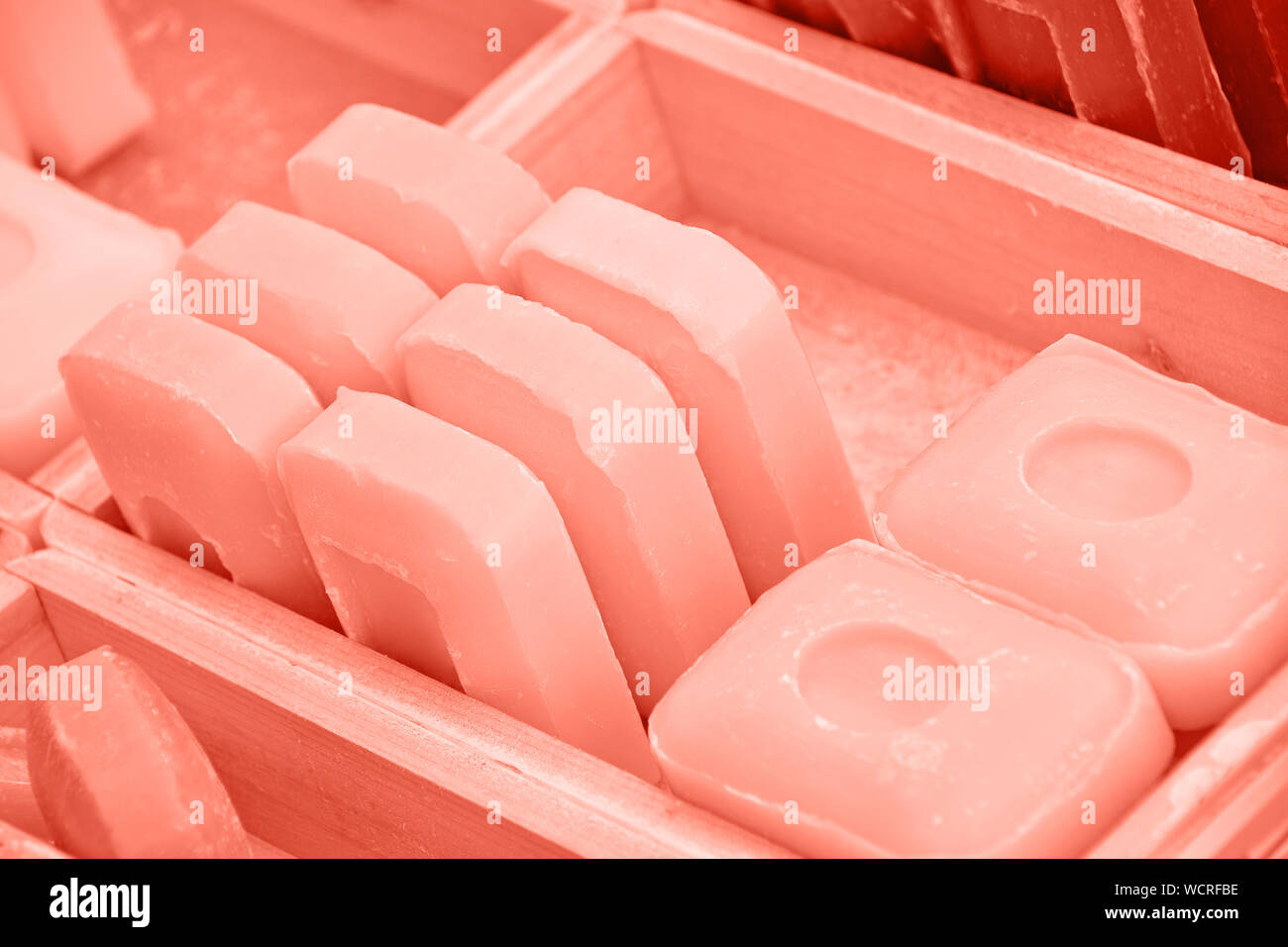 Close up coral pink toned traditional beauty toilet hard soap bars in wooden box on retail display, high angle view Stock Photo