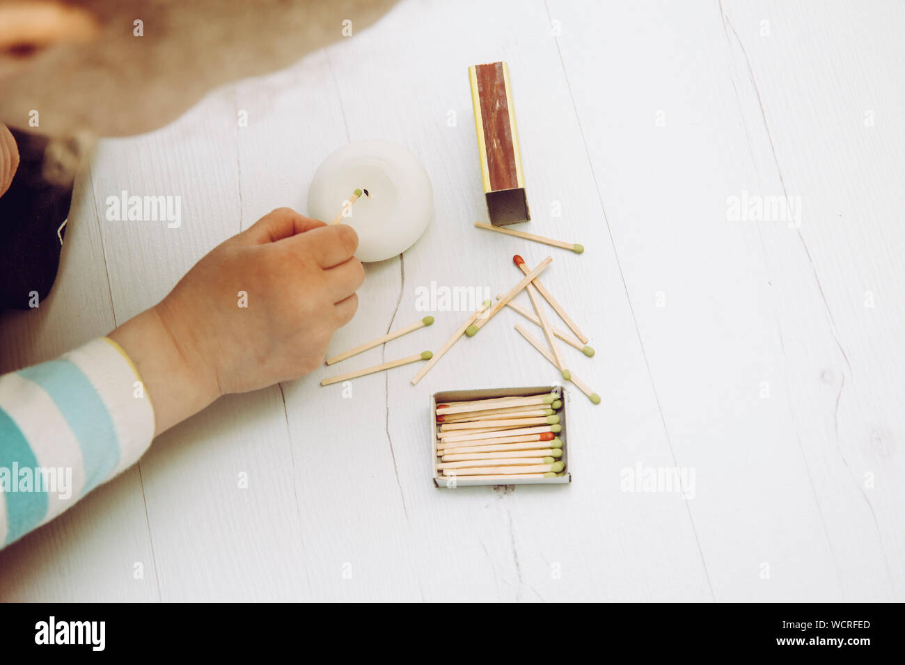 Close up view of child playing with fire, matches and lighting a candle