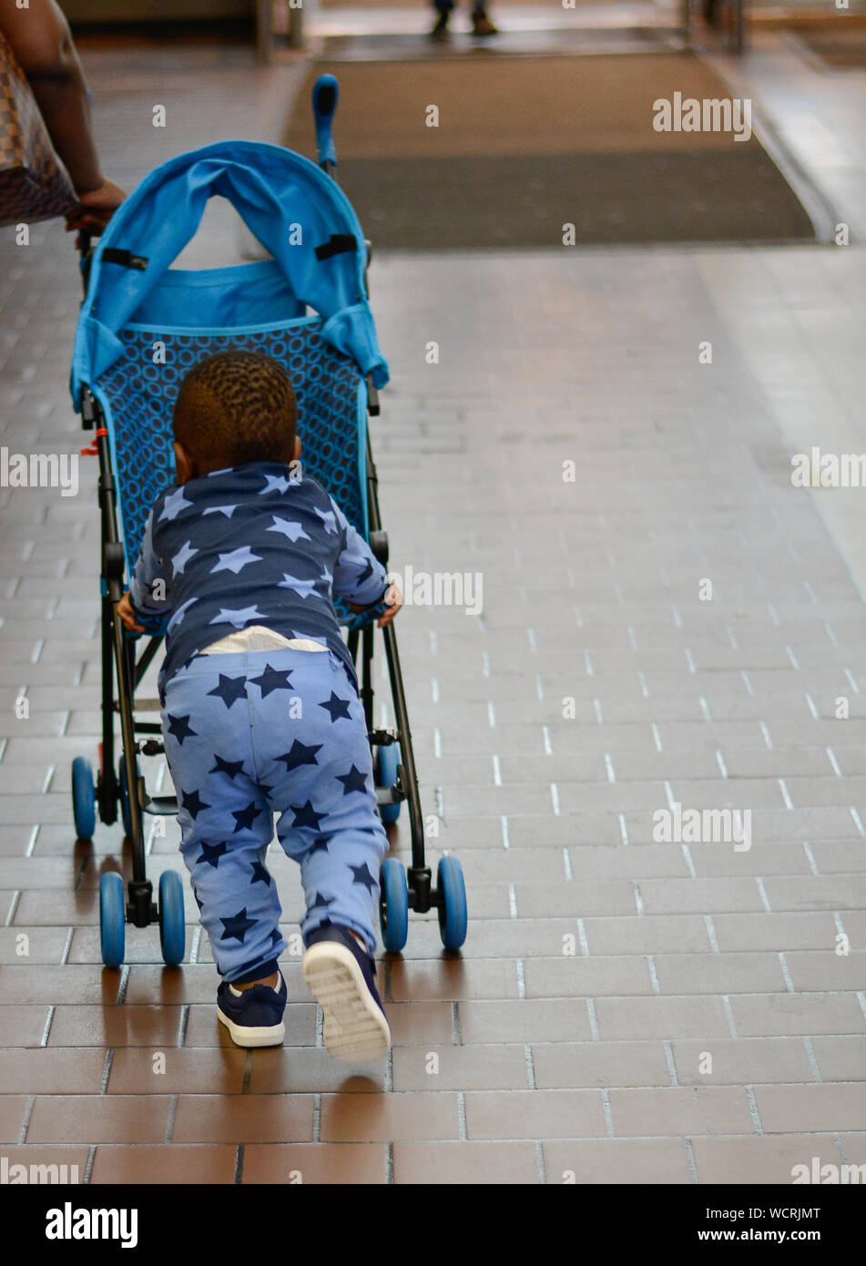 Rear View Of Boy Pushing Baby Stroller On Footpath Stock Photo - Alamy