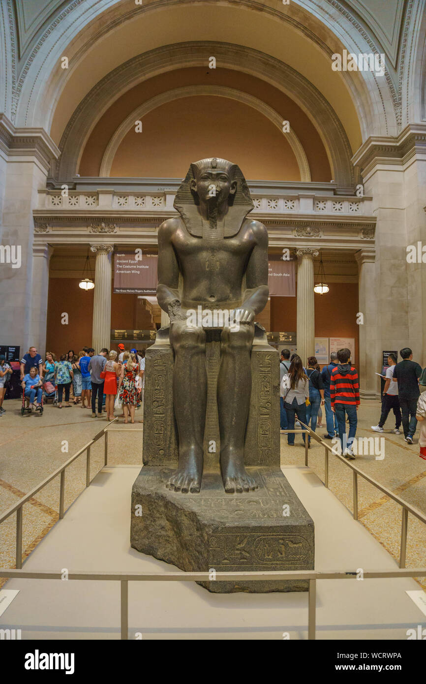 A monumental ancient Egyptian statue of a seated pharaoh at the
