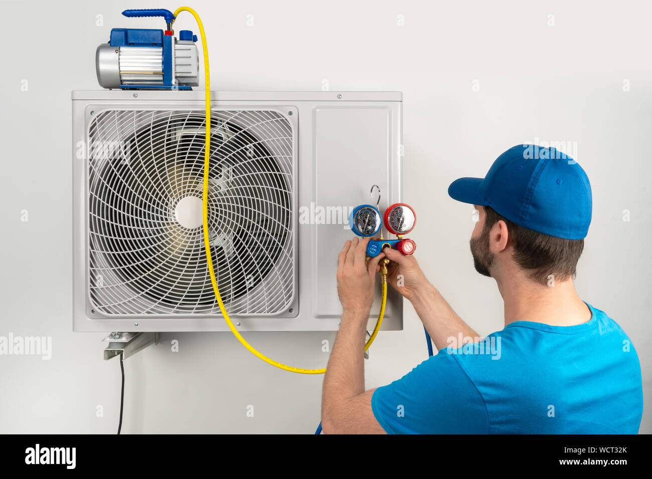 Installation service fix  repair maintenance of an air conditioner outdoor unit, by cryogenist technican worker evacuate the system with vacuum pump a Stock Photo