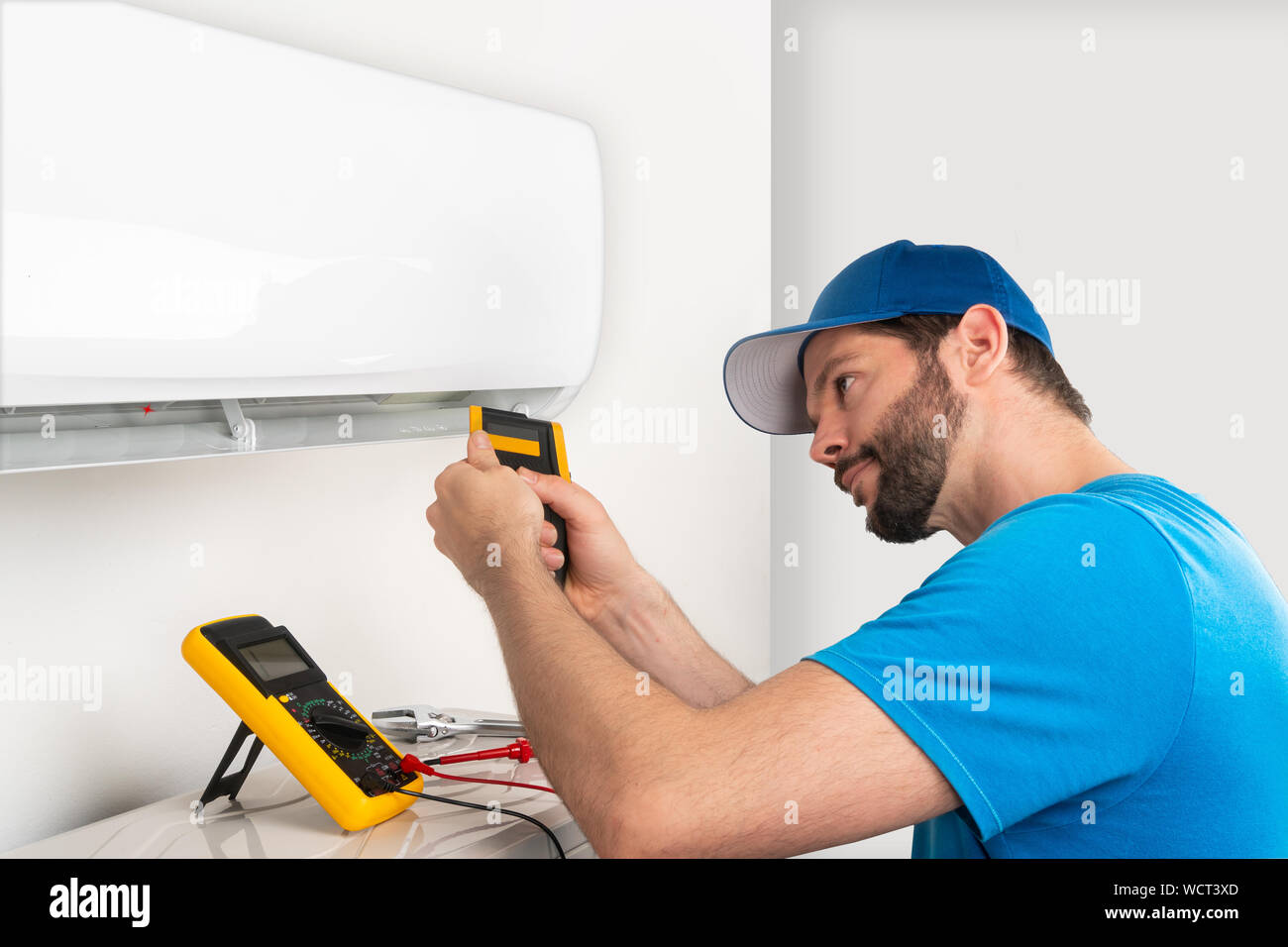 Installation service fix  repair maintenance of an air conditioner indoor unit, by cryogenist technican worker checking the temperature with infrared Stock Photo