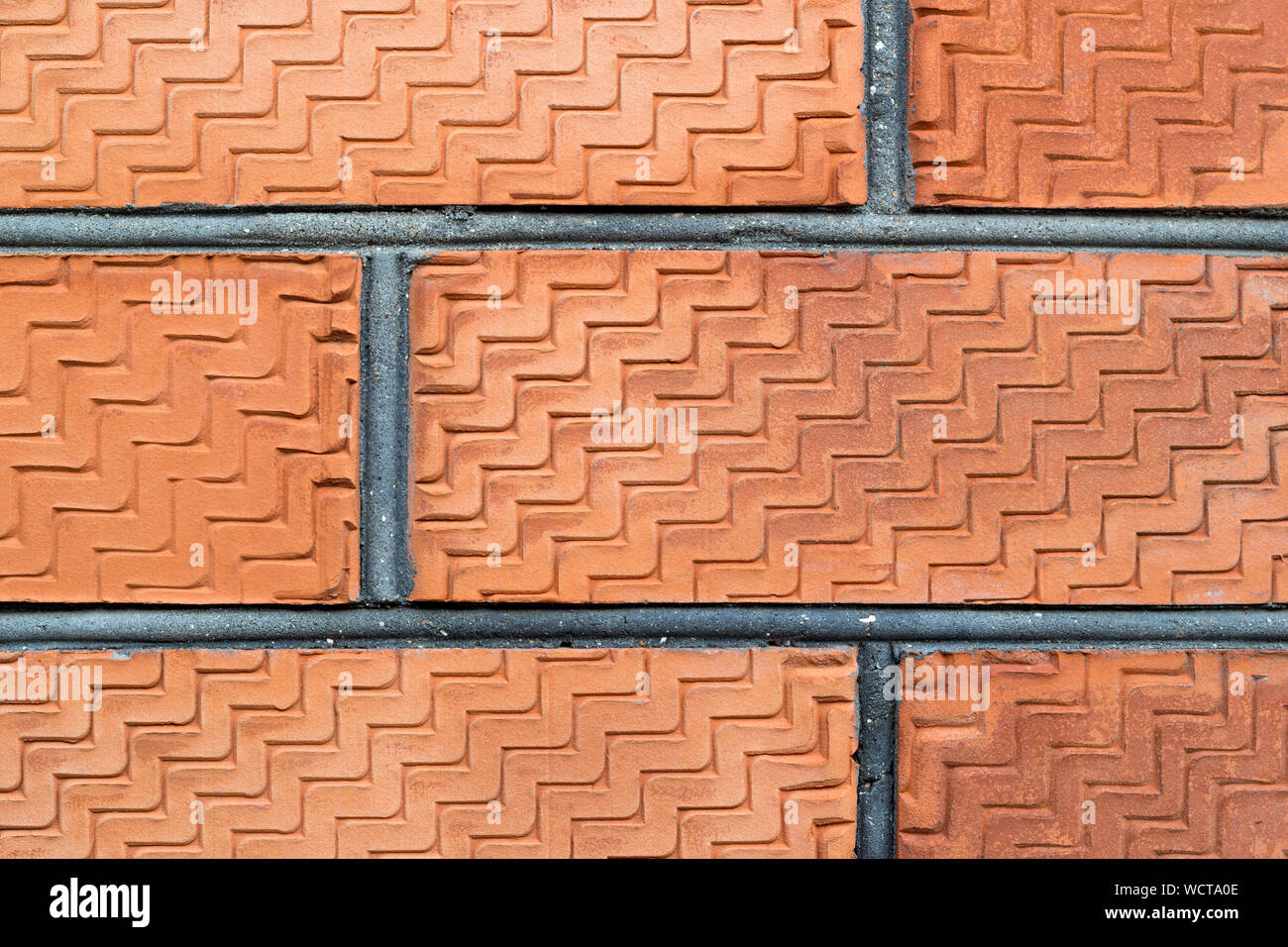 Weathered stained old red brick wall background. Close-up. A pattern carved on the surface. Zigzag texture. Copy space. Construction outdoor photograp Stock Photo