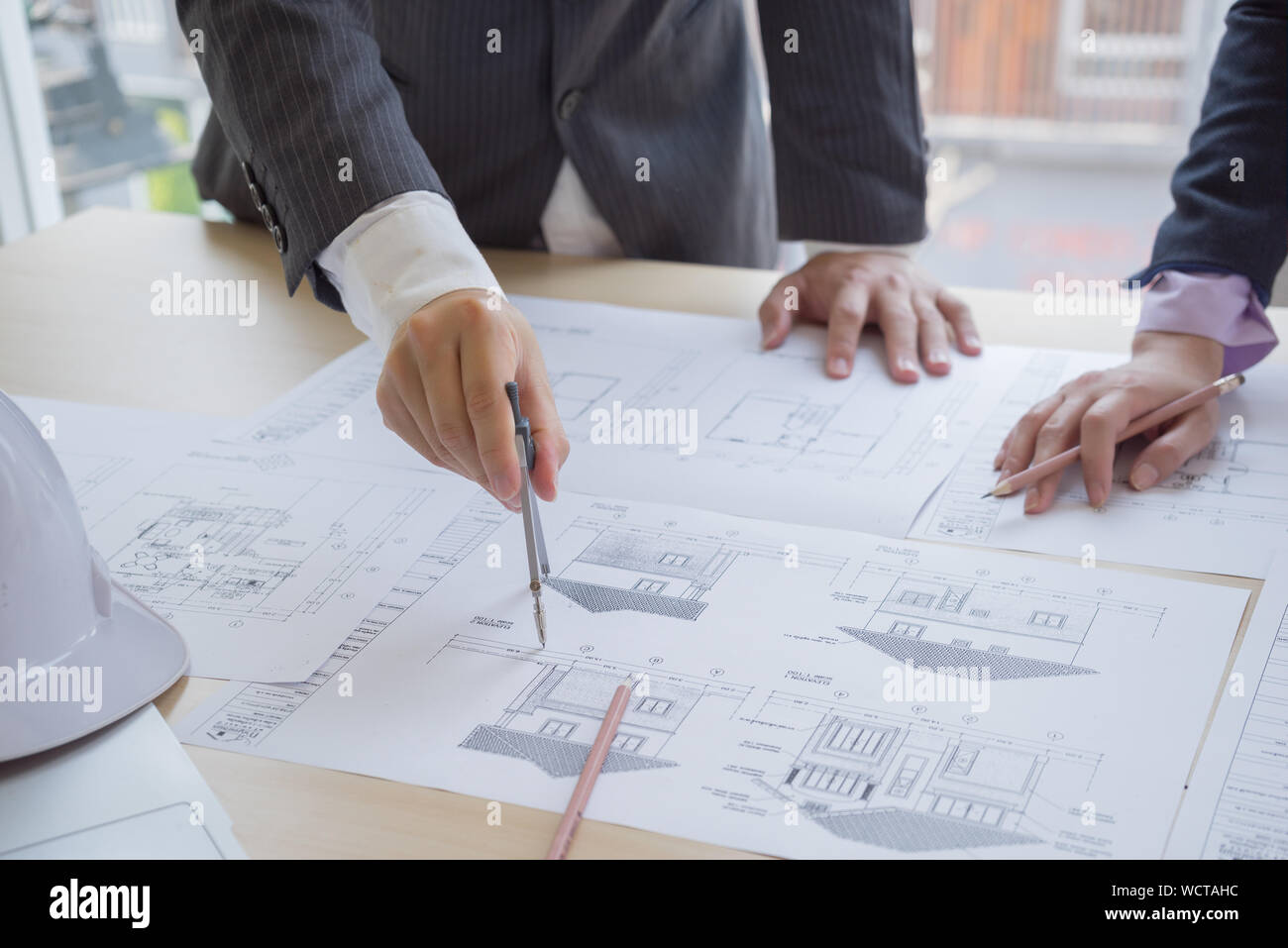 Close-up Architectures Discussing Over Blueprint At Desk In Office Stock Photo