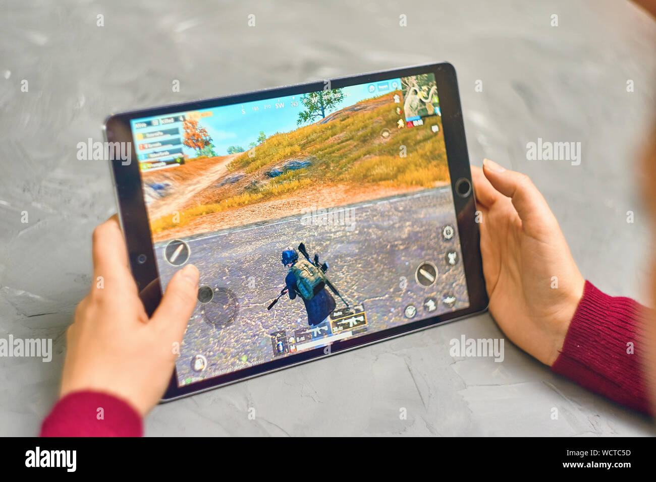 Bishkek, Kyrgyzstan - January 21, 2019: Woman playing pubg coop multiplayer battle royale game on Apple ios tablet iPad Pro Stock Photo