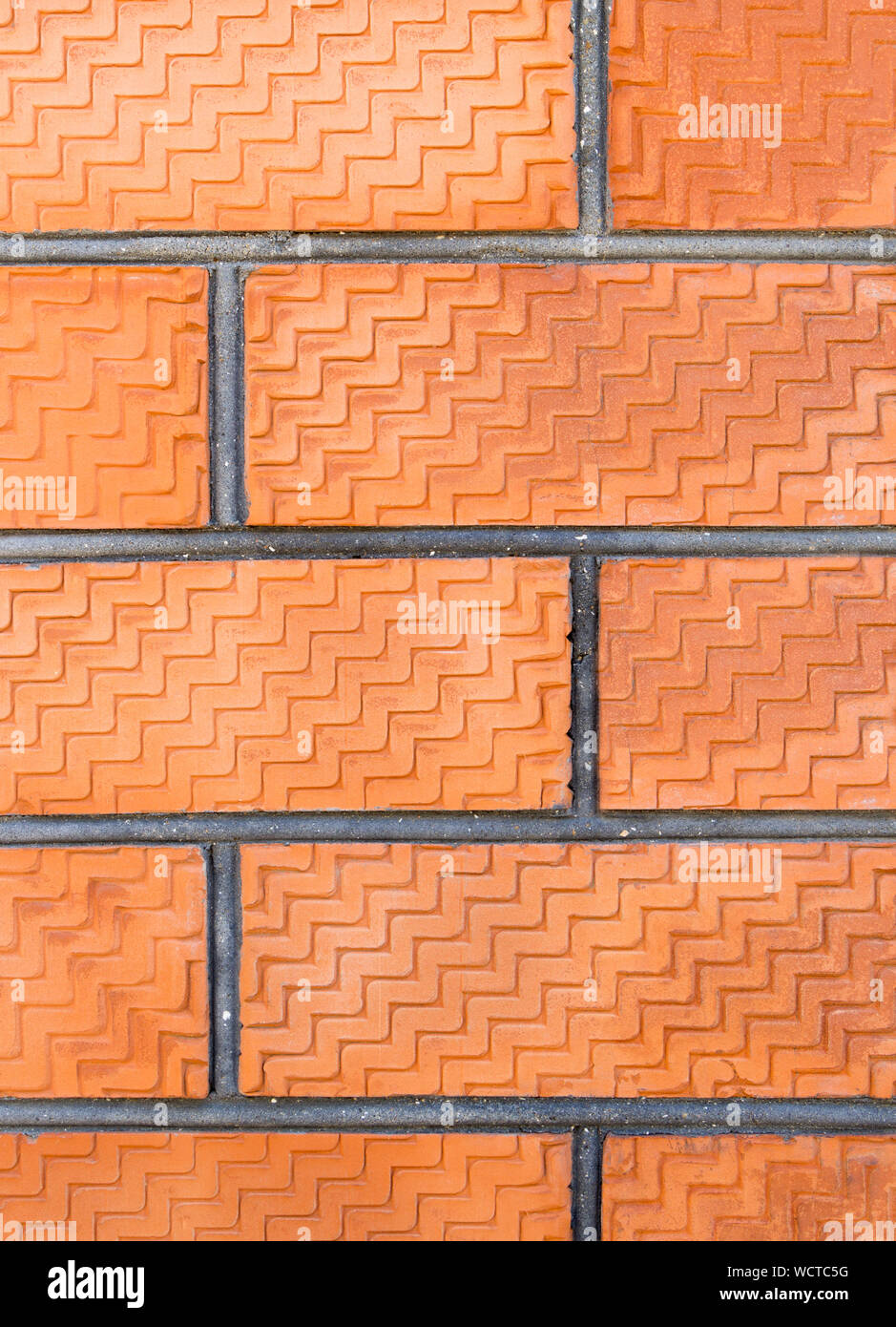 Close up weathered red brick wall texture for background. Vertical photography. Decorative lining of the house. Wavy pattern on a brick surface. Const Stock Photo