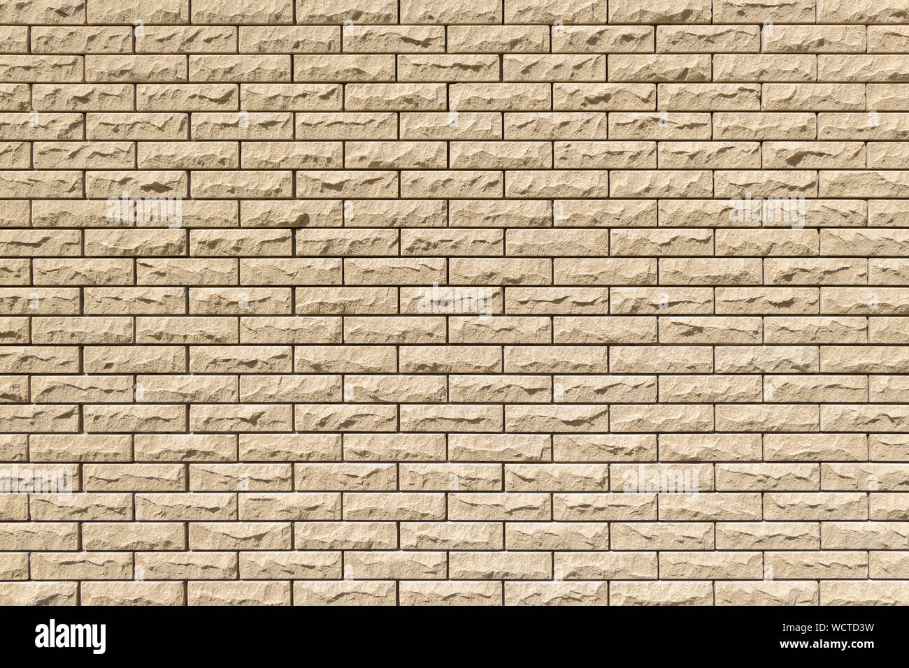 Close-up detail of a sand brick wall texture for background. Horizontal masonry. Copy space. Beautiful decorative bricks with rellief surface. Vertica Stock Photo