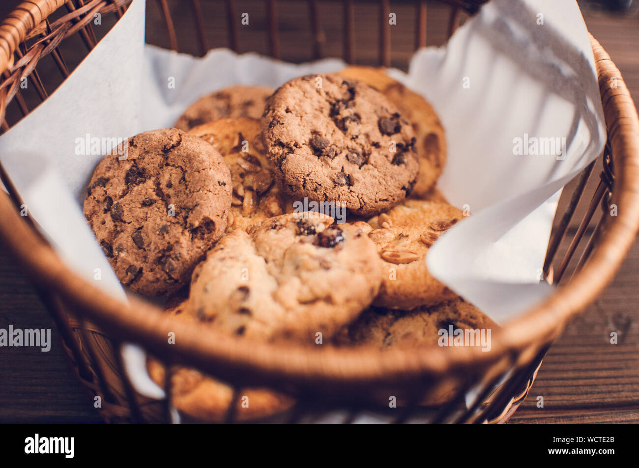 Cookies with chocolate lies in a wicker basket. A basket with gluten free cookies on a wooden table. Selective focus. Stock Photo