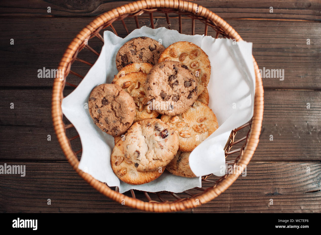Cookies with chocolate lies in a wicker basket. A basket with gluten free cookies on a wooden table. Selective focus. Stock Photo
