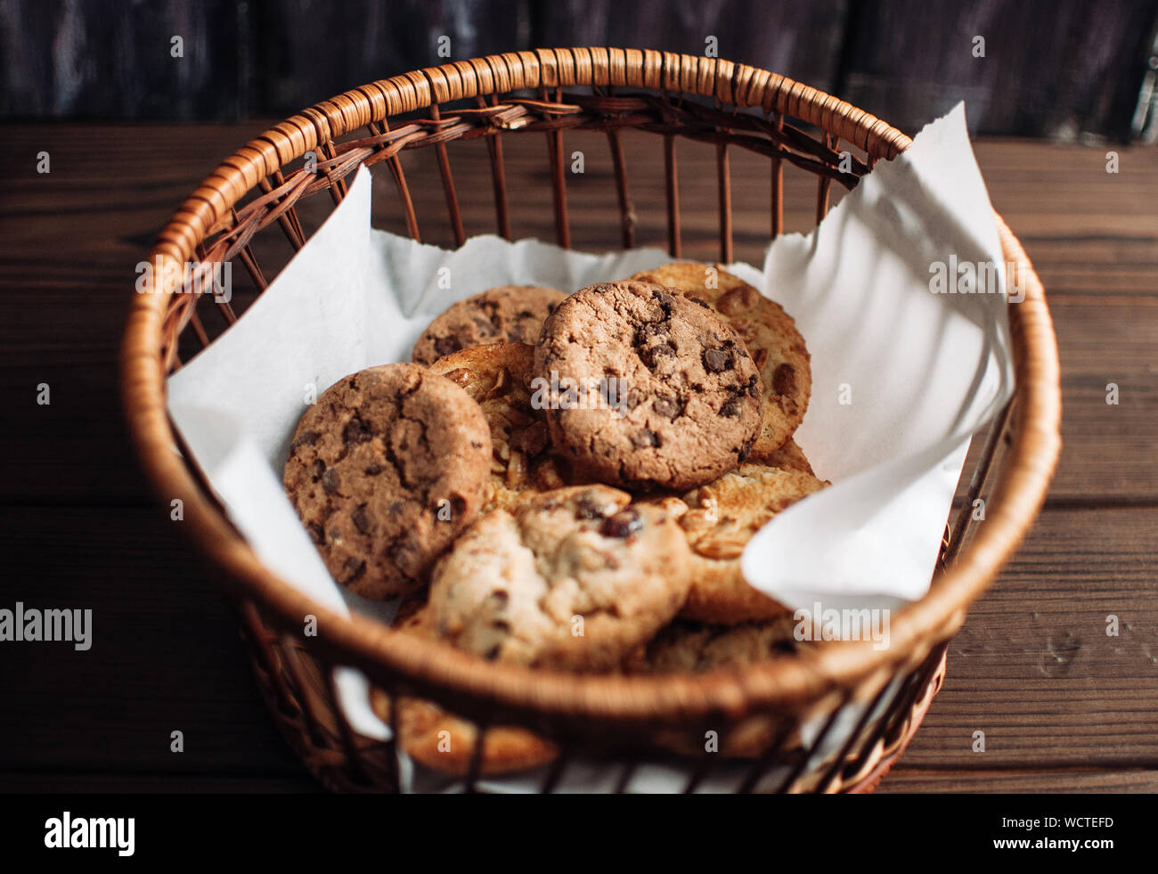 Cookies with chocolate lies in a wicker basket. A basket with gluten free cookies on a wooden table. Selective focus. Stock Photo