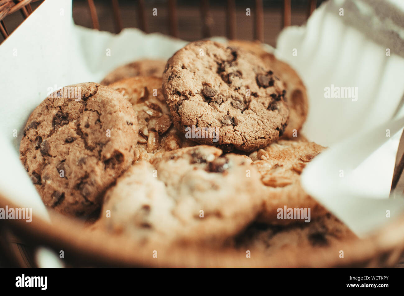 Cookies with chocolate lies in a wicker basket. A basket with gluten free cookies on a wooden table. Selective focus. Stock Photo
