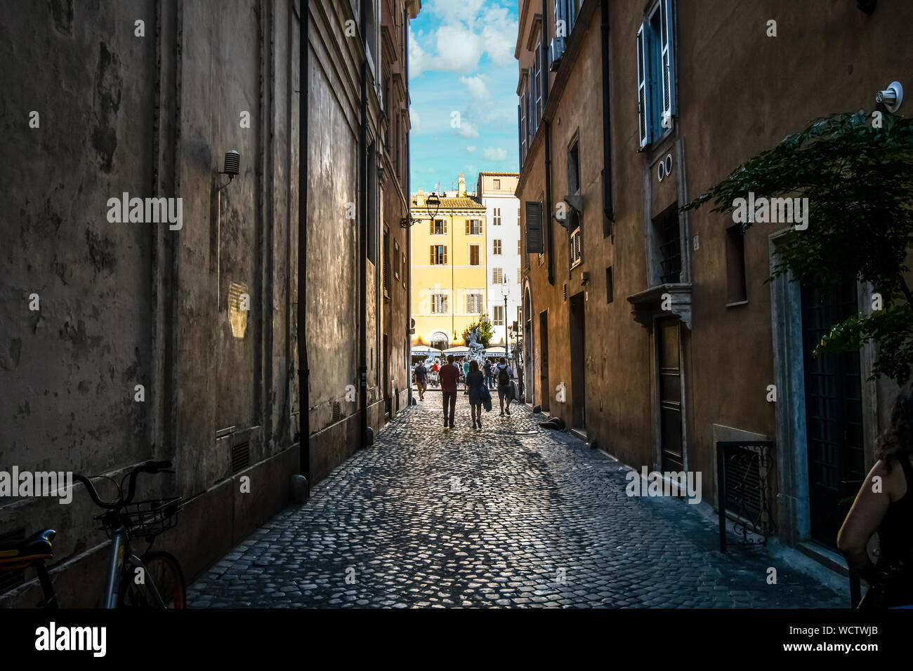 A couple walks down a narrow alley towards the Piazza Navona in Rome, Italy. Stock Photo