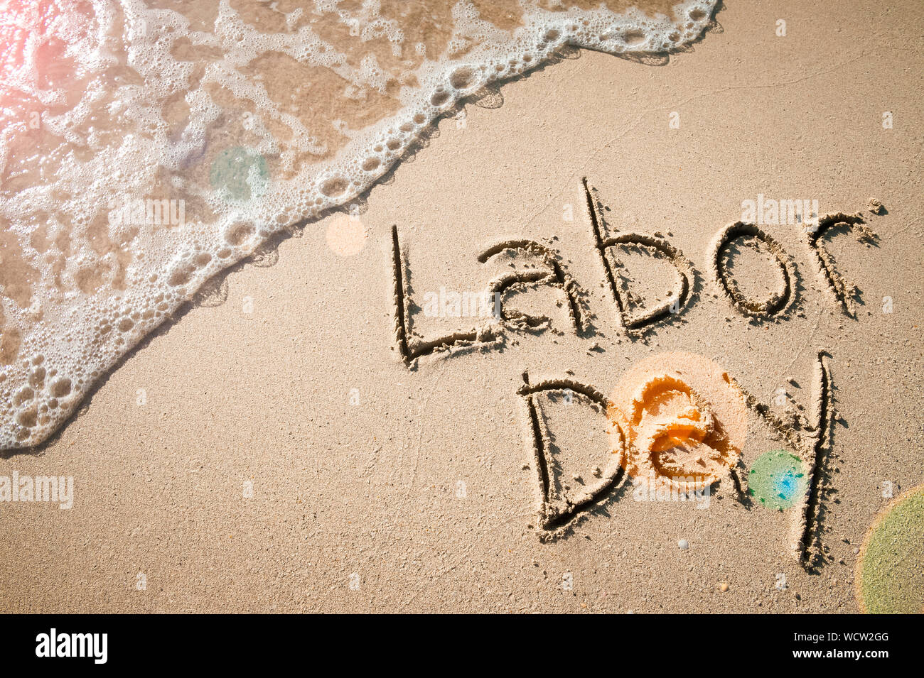 Labor Day message handwritten on the smooth sand of an empty beach with ...