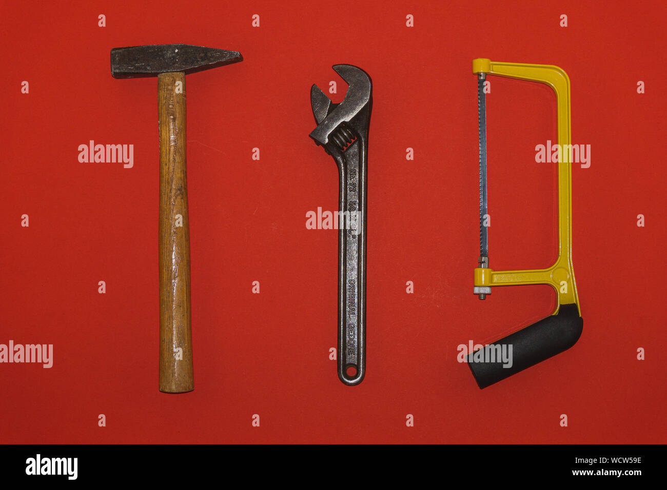 Metal hammer, wrench, and saw on red background Stock Photo Alamy