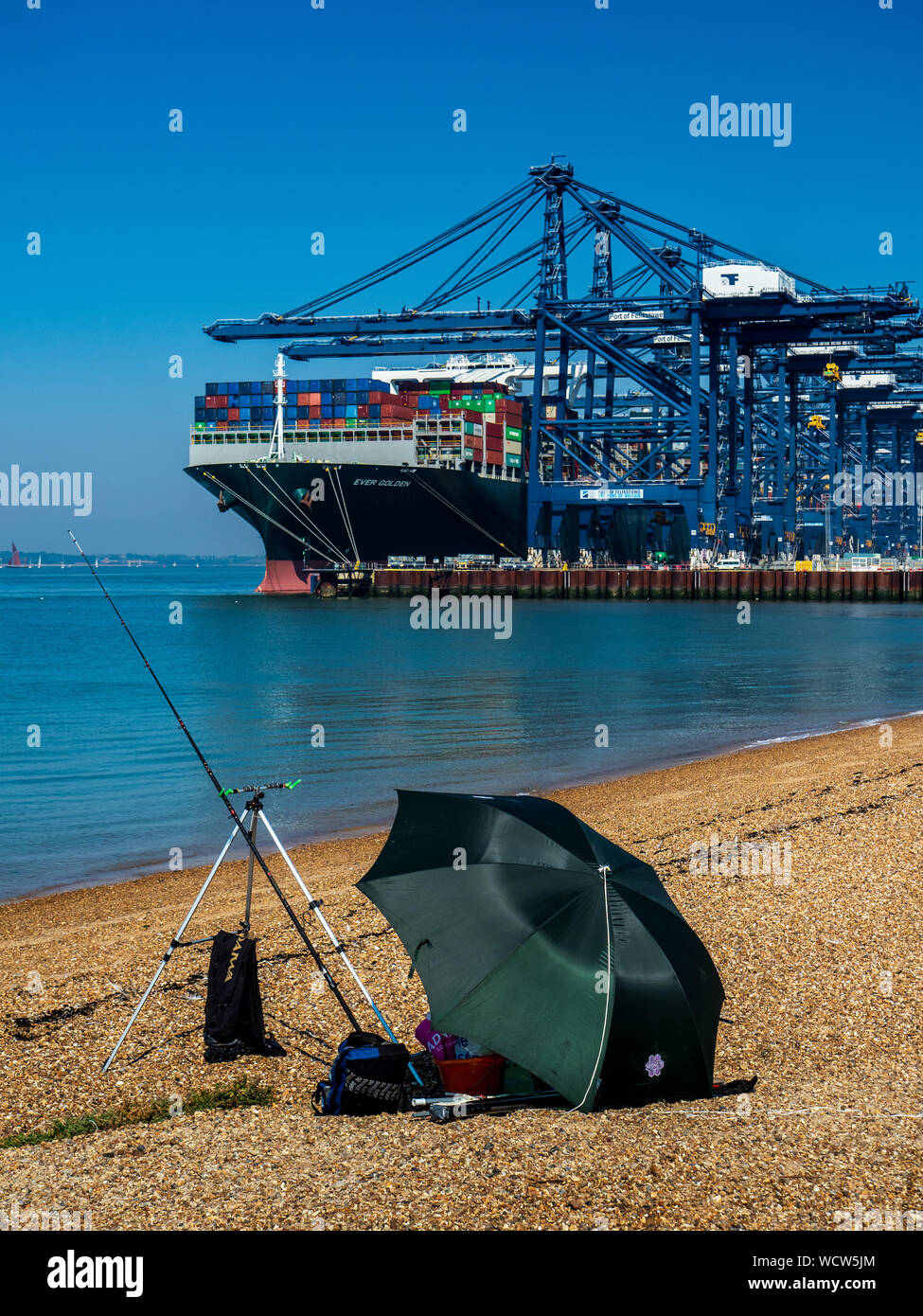 Felixstowe Container Port - The Ever Golden Container Ship unloads cargo at the Port of Felixstowe UK watched by a beach fisherman. Stock Photo