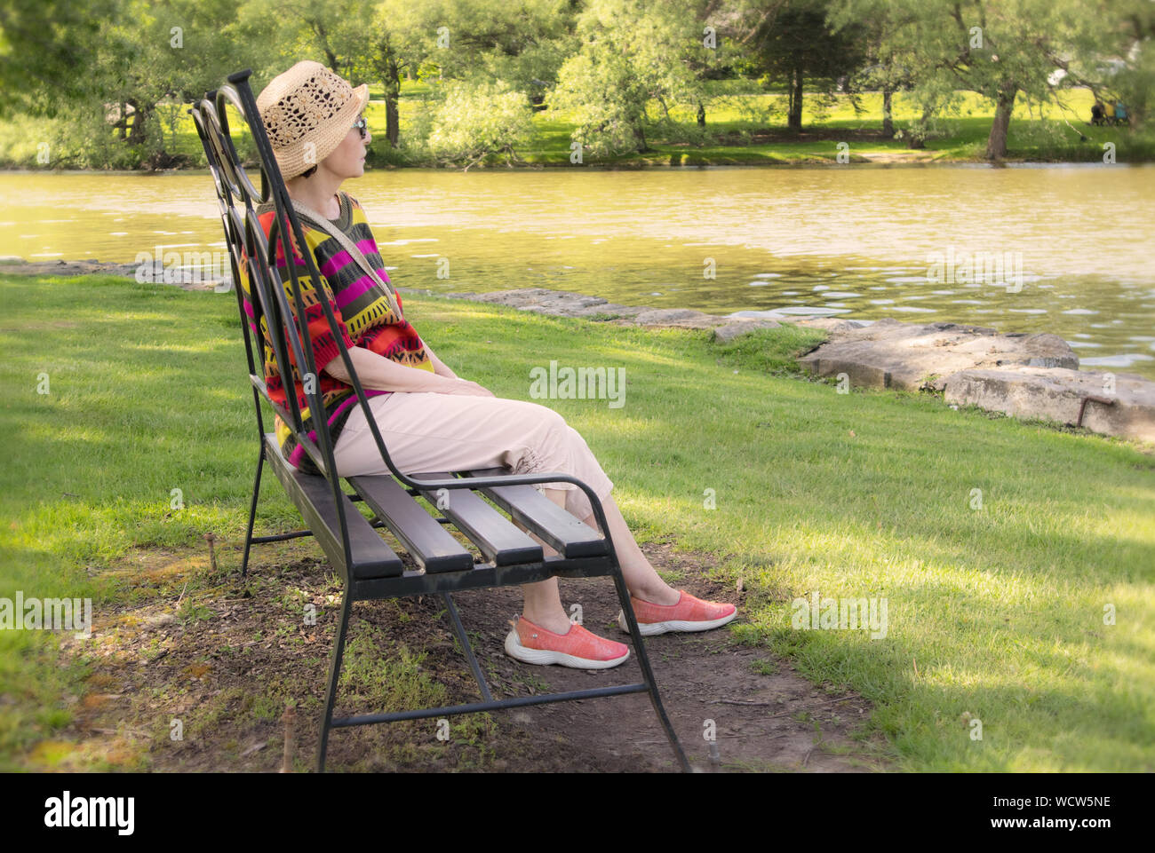 A mature woman sitting on a park bench and watching in front of her ...