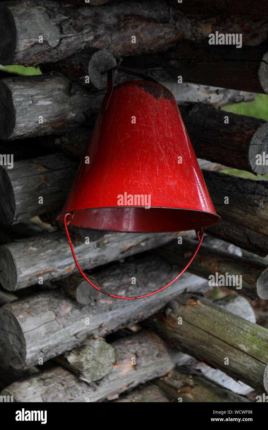 Red extinguishing bucket by a fireplace in the wilderness Stock Photo