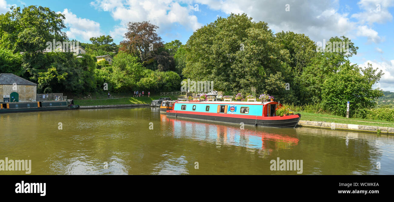 BATH, ENGLAND - JULY 2019: Panoramic view of a coloured house boat decorated with flowers moored on the Kennet & Avon Canal near the city of Bath Stock Photo