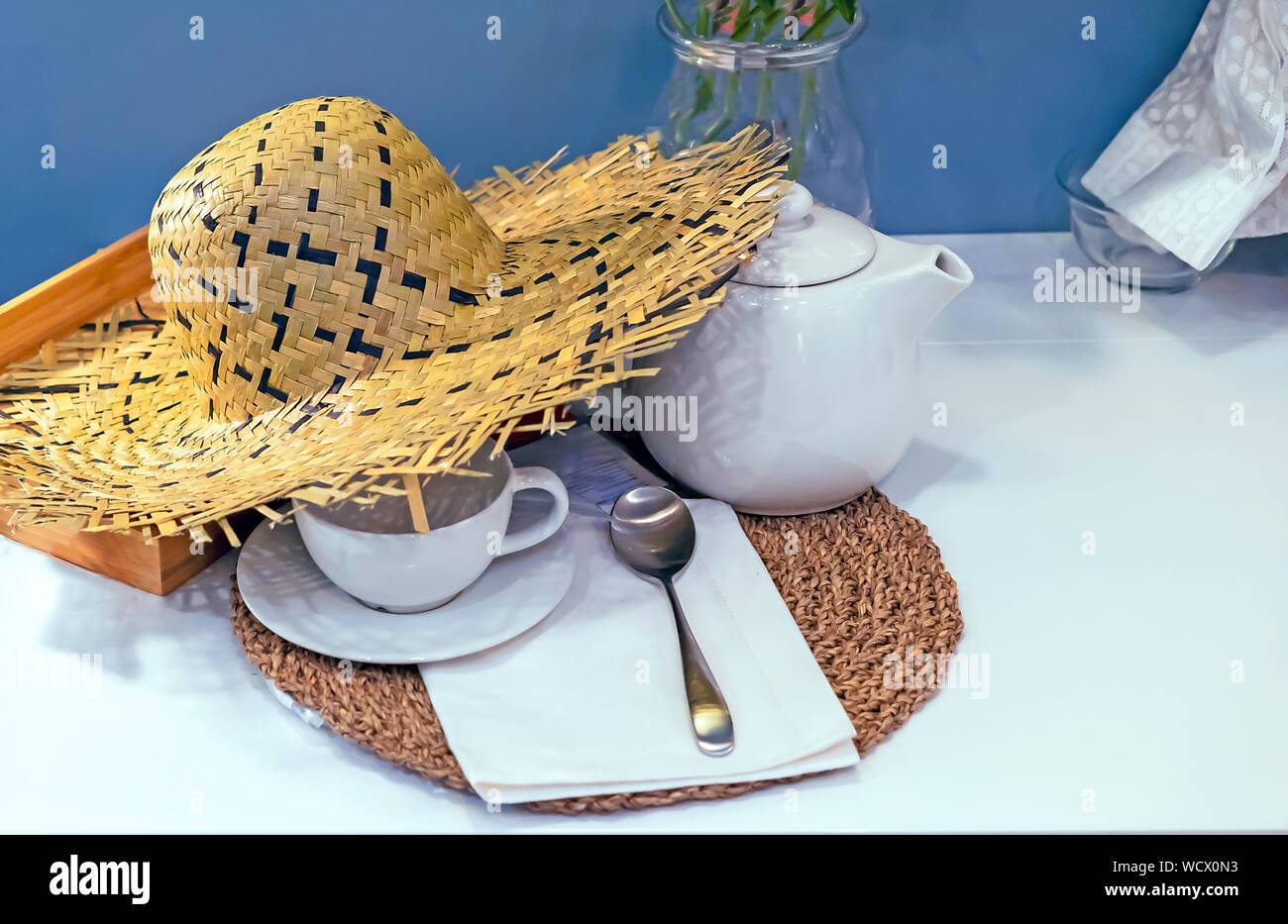 Straw hat on the table with tea appliances. Stock Photo