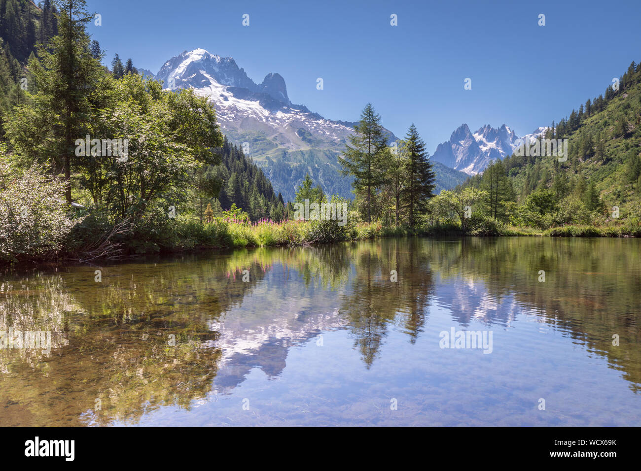 Alps reflected in a mountain lake close to Chamonix and Argentiere. The Aiguille Verte, Les Drus and the Aiguilles de Chamonix veiwed across a lake ne Stock Photo