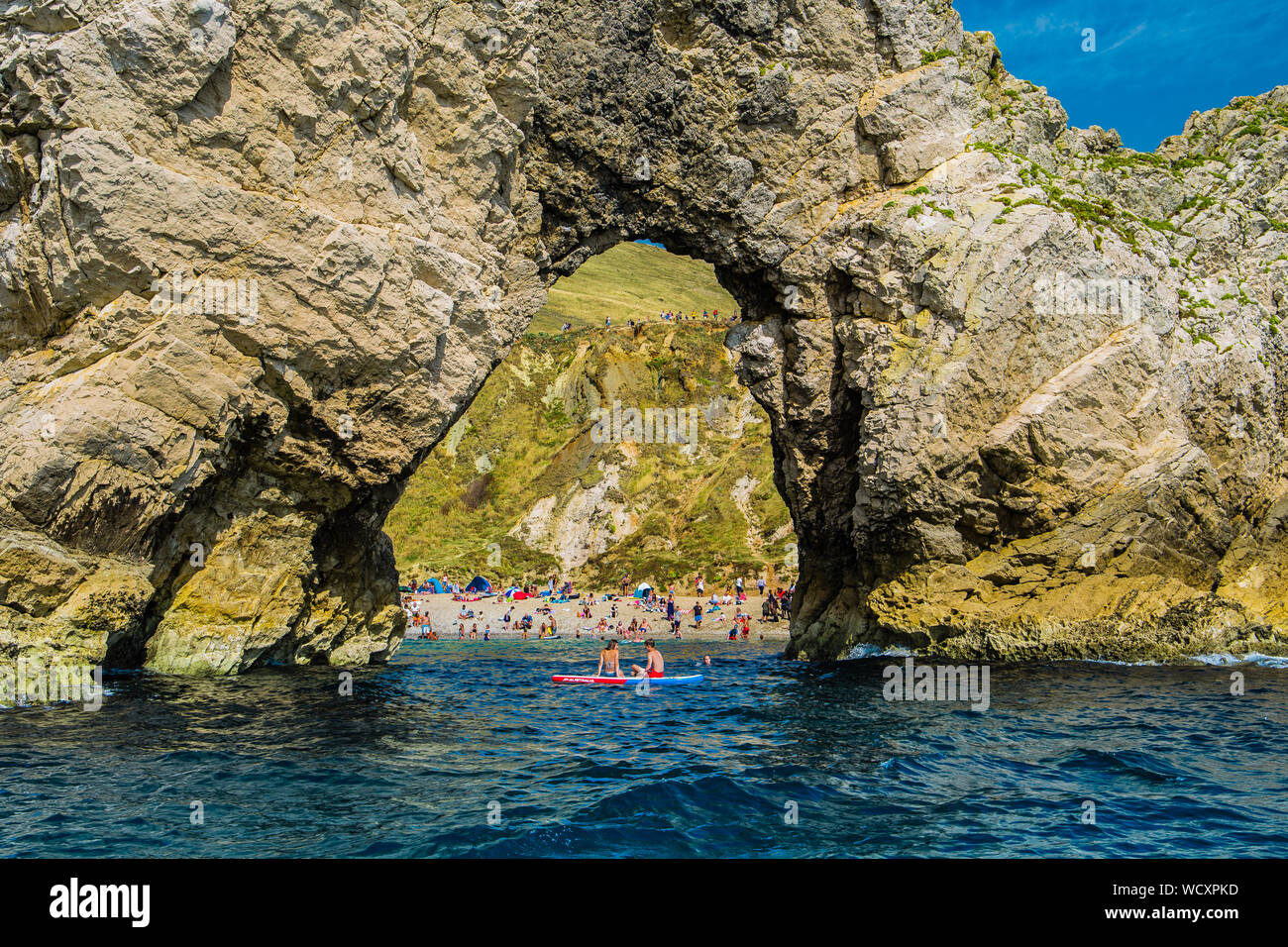 Holidaymakers at Durdle Door beach on the Jurassic Coast, Dorset, England, UK Stock Photo