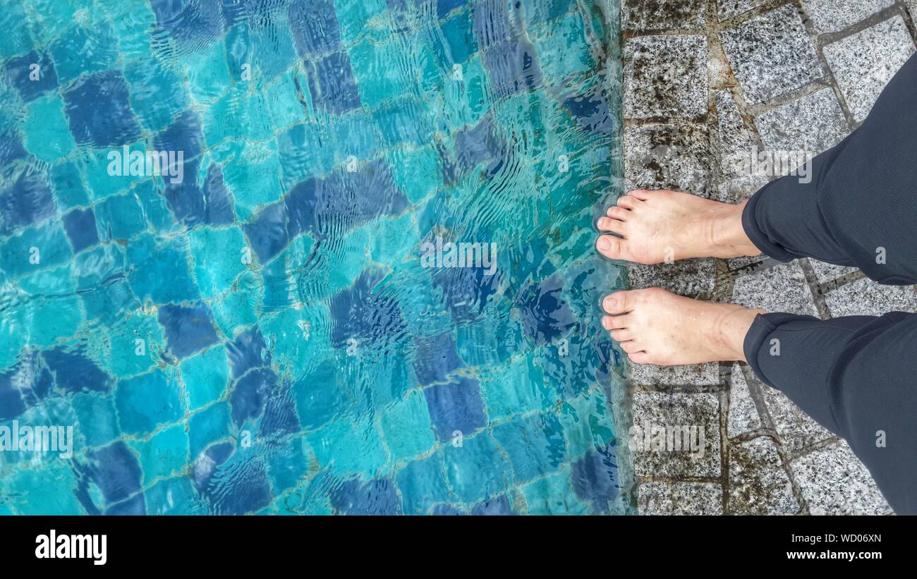 Low Section Of Person Standing At Pool Side Stock Photo