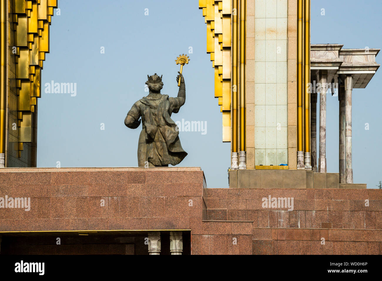 The bronze statue of the Ismail Somoni Monument raises a scepter between the gilded struts of the arch in Rudaki Park in Dushanbe, Tajikistan, the Tajik currency, the somoni, named after the ruler. Stock Photo